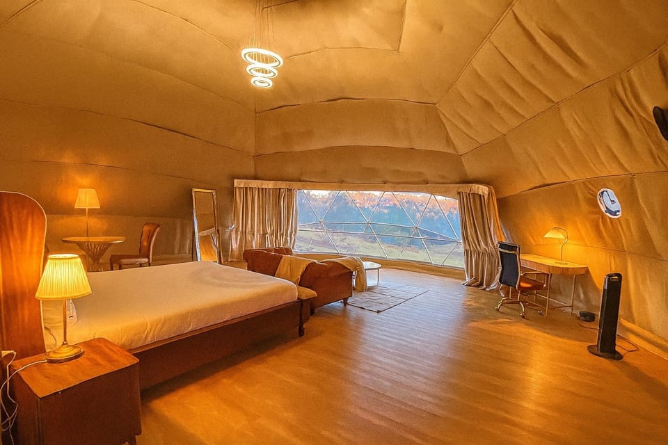 The bed, seating and large window inside the warmly lit dome