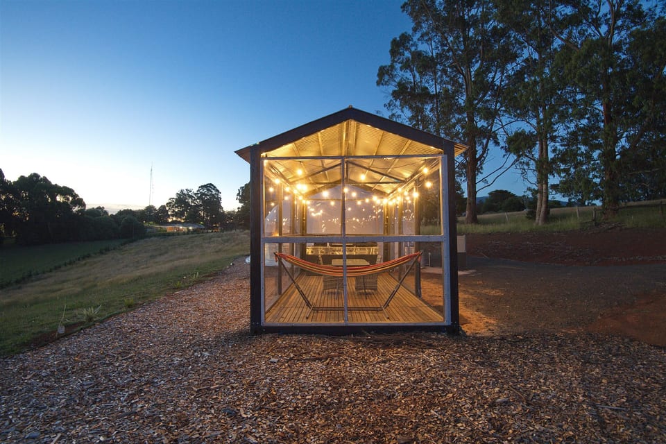 The dome's outdoor pavilion with warm lights, dining table and countryside views